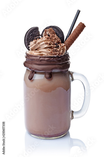 Crazy chocolate milk shake with whipped cream, cookies and black straw in glass jar