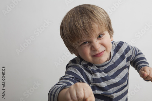 Niño (5 años) desafiante con un puño de la mano delante y otro detrás. photo