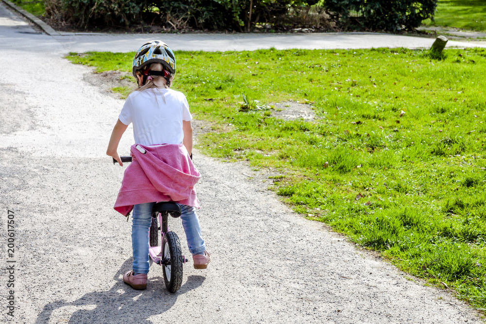 Fototapeta premium Little girl riding on her pink bike