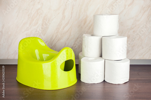 children's toilet pot green and toilet paper, the concept of moving the baby from diapers to the toilet photo