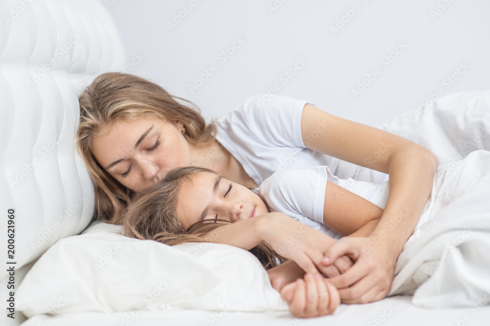 Mom and daughter sleep together on the bed in the bedroom Mom and daughter sleep together on the bed in the bedroom