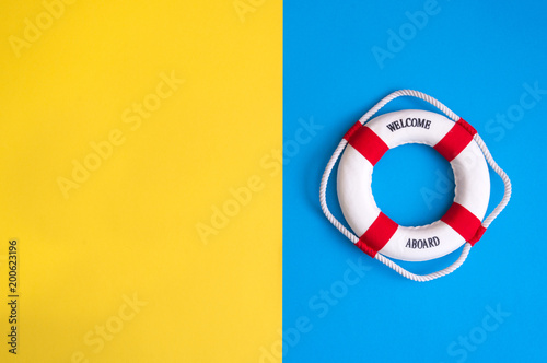 Lifebuoy on a yellow and blue background with blank space for text. Top view travel or vacation concept. Summer background. Flat lay photo, top view.
