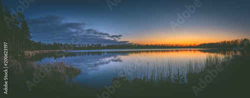 Fototapeta Naklejka Na Ścianę i Meble -  Colorful sunset over the lake in late evening in Spring. Peaceful scenery with clear sky and reflections in water.