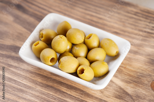 Olives in a bowl on wooden surface