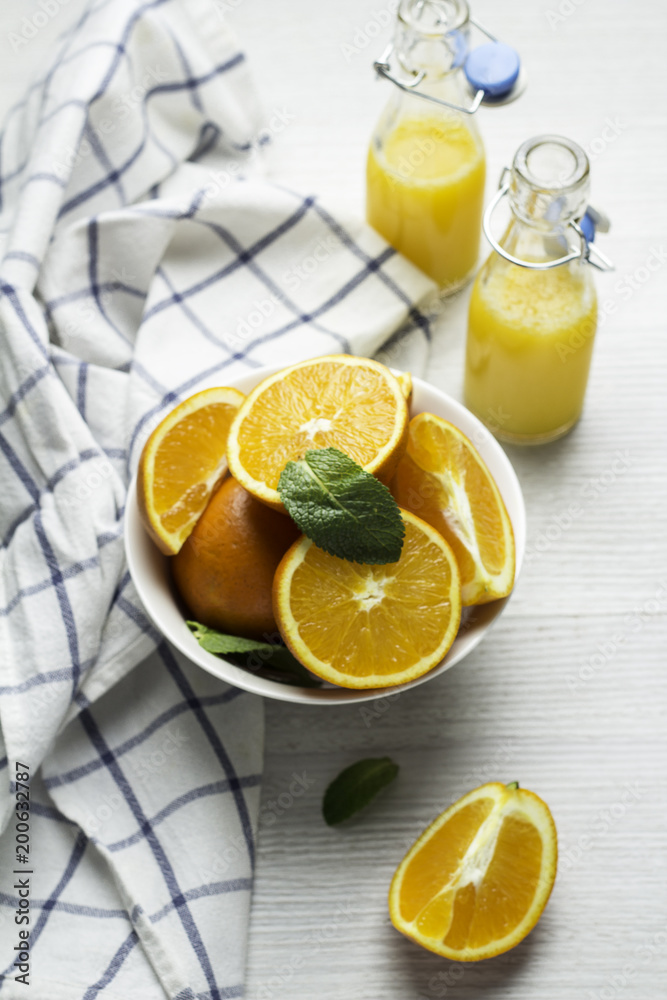 oranges in a white cup, mint leaves and orange juice on a white background. oranges in a white cup, mint leaves and orange juice on a white background.