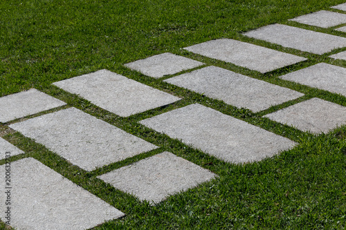 Stepping stone path through green mown grass diagonal way