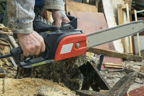 A man sifts a saw with firewood