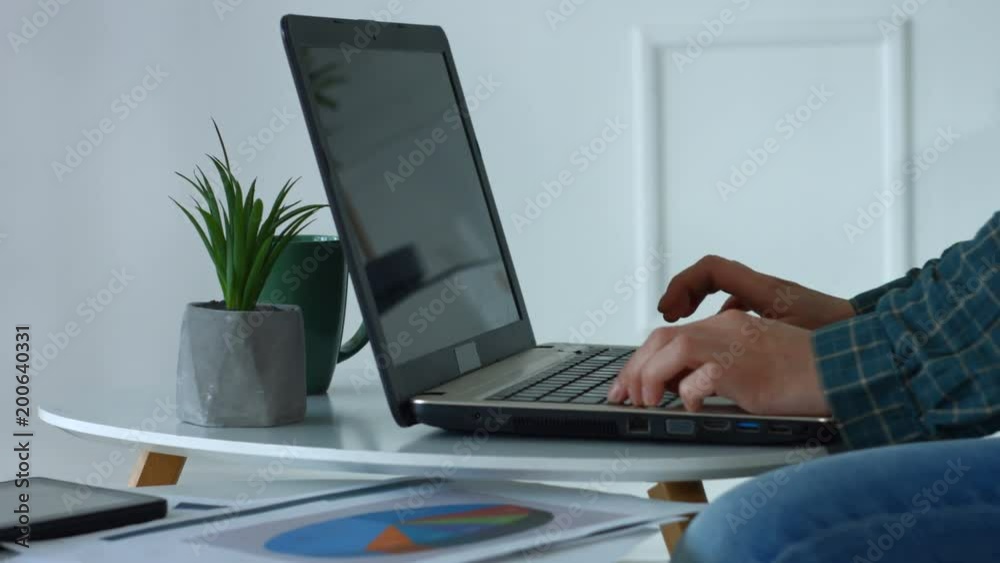 Female hands typing on laptop keyboard in domestic room on desk with digital tablet and financial graphs. Closeup. Woman's hands pressing keys on laptop keyboard trying to access data in home office. Female hands typing on laptop keyboard in domestic room on desk with digital tablet and financial graphs. Closeup. Woman's hands pressing keys on laptop keyboard trying to access data in home office.