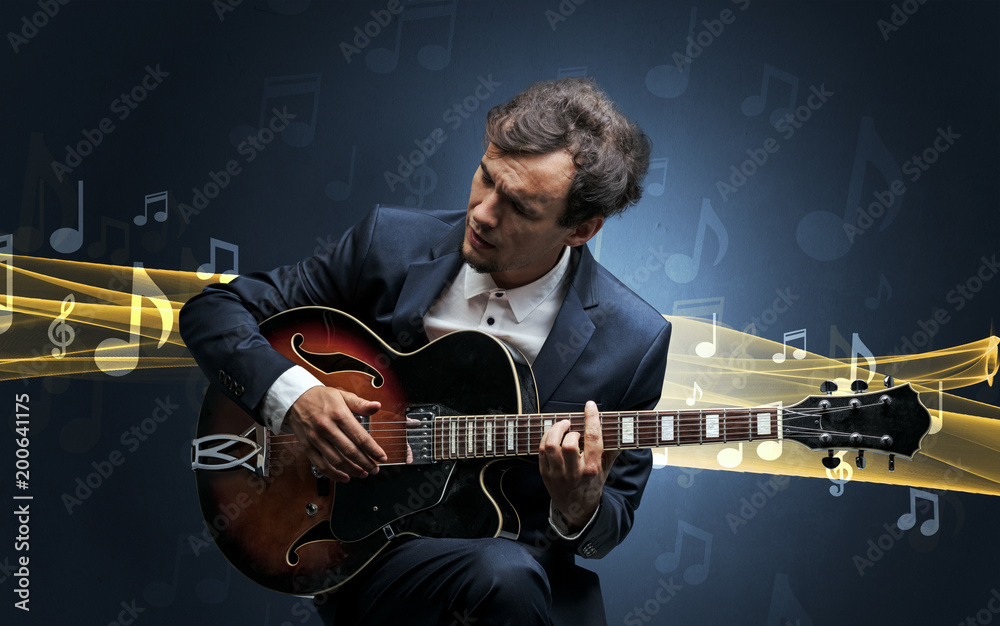 Obraz premium Young male musician playing on his guitar with musical notes around