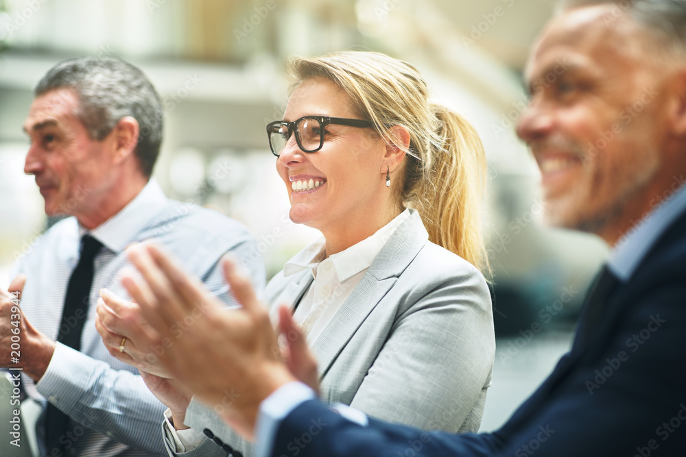 Smiling mature businesswoman and colleagues clapping during an o Smiling mature businesswoman and colleagues clapping during an o