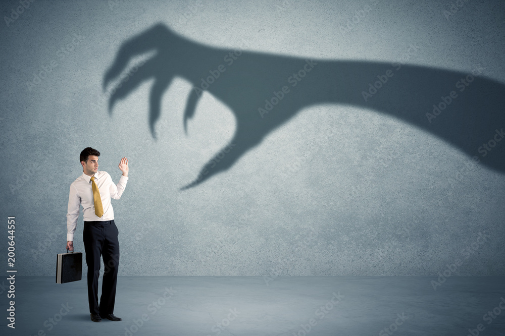 Fototapeta premium Business person afraid of a big monster claw shadow concept on background