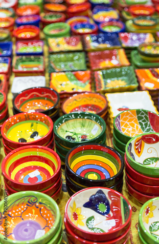 Colourful hand painted bowls and pots arranged in rows on market stall