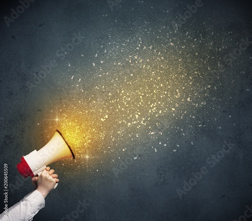 Caucasian business hand holding megaphone with yellow sparkles