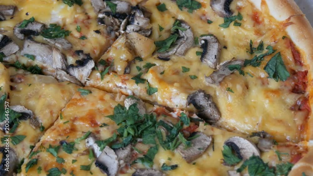 Woman's hand takes piece of round pizza withwith greens, chicken, mushrooms and double cheese Woman's hand takes piece of round pizza withwith greens, chicken, mushrooms and double cheese