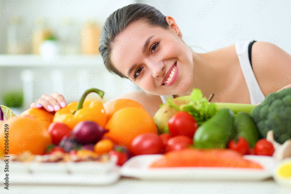 Young and cute woman sitting at the table full of fruits and vegetables in the wooden interior Young and cute woman sitting at the table full of fruits and vegetables in the wooden interior