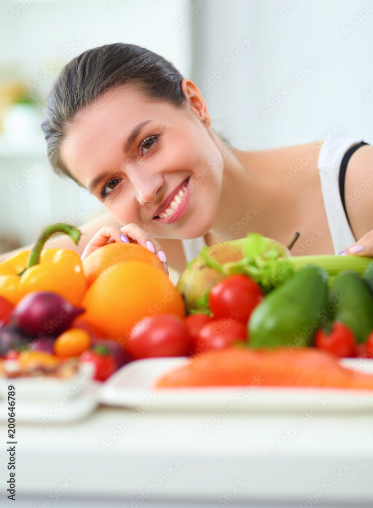 Young and cute woman sitting at the table full of fruits and vegetables in the wooden interior Young and cute woman sitting at the table full of fruits and vegetables in the wooden interior