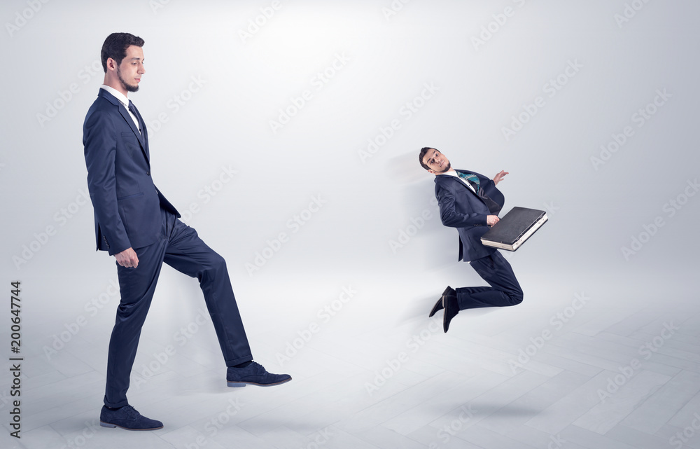 Fototapeta premium Small young man fired by his bos from his workplace with suitcase on his hand 
