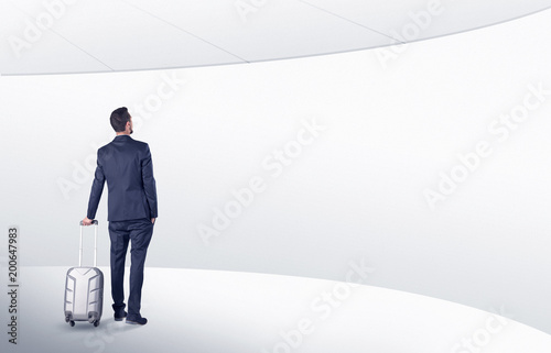 Businessman with back walking in a white waiting room with empty walls around 