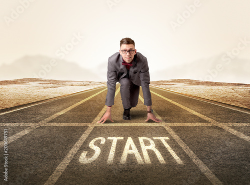 Young determined businessman kneeling before start line