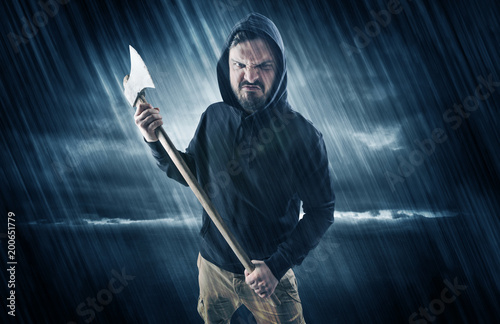 Masked armed poacher in mysterious rainy coastal weather concept 