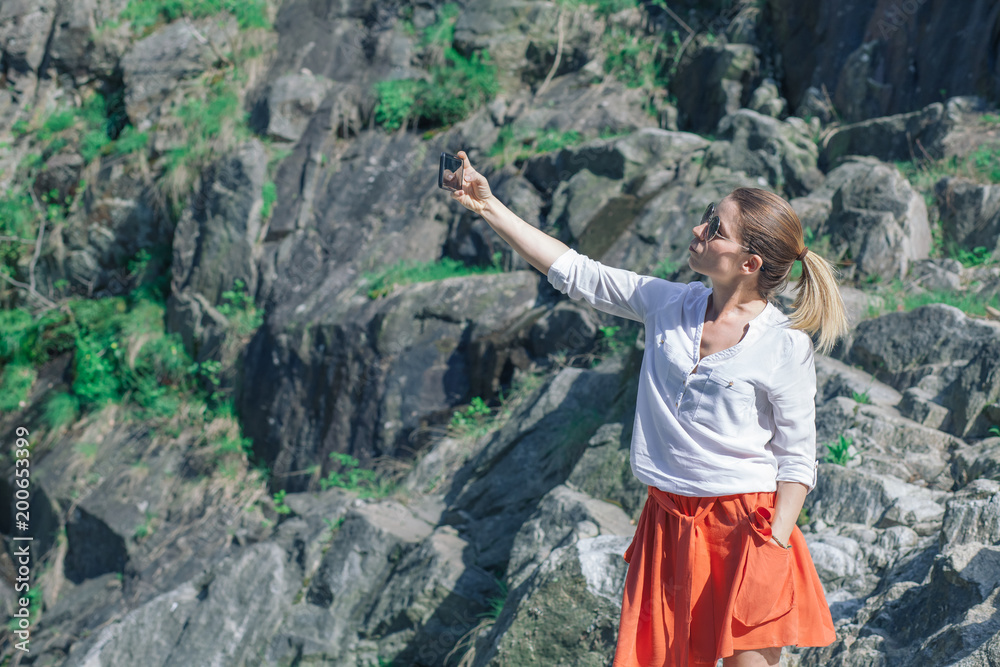 Obraz premium Young woman using smartphone on the lake in the springtime