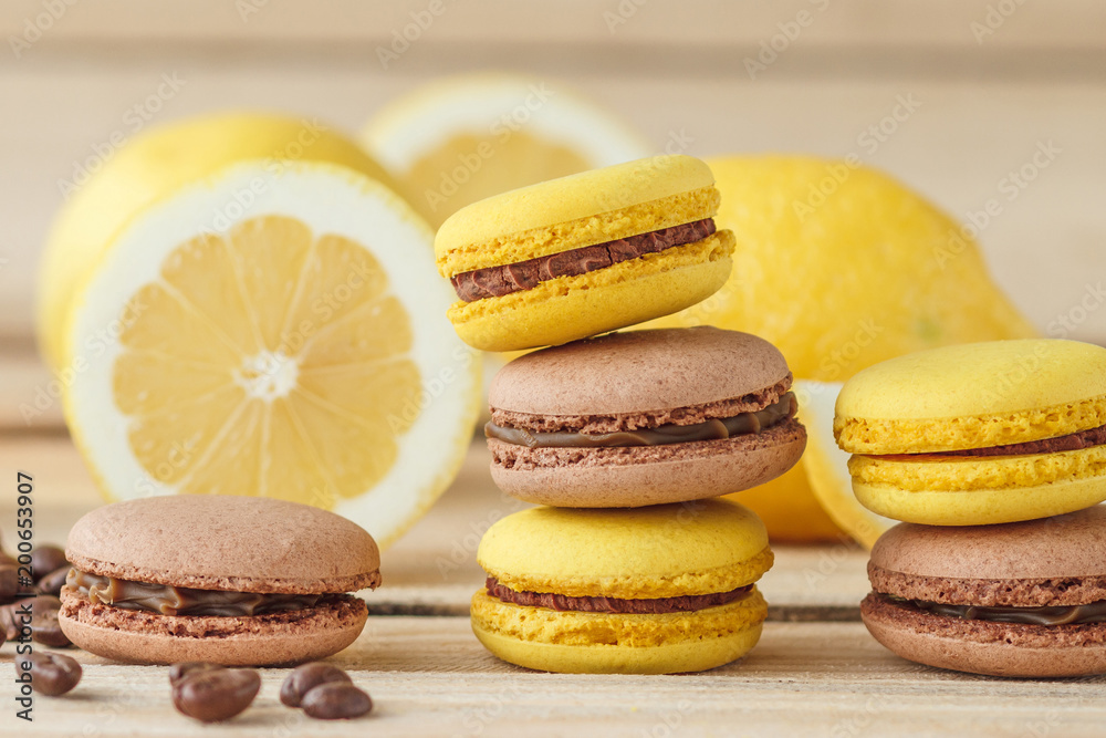 Yellow and brown french macarons with lemons and coffee beans on the wooden board