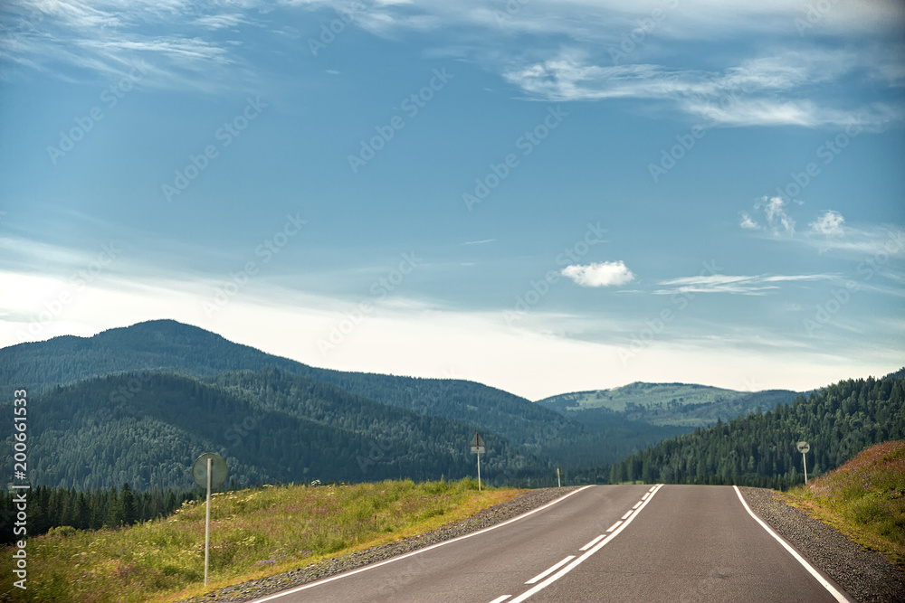 highway through hills and clouds on sky