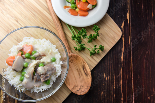 Chicken fricassee with green pea served with boiled rice on a wooden background. photo