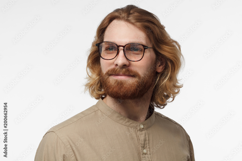Close up side headshot of smiling attractive bearded man in dark green shirt isolated on gray background Close up side headshot of smiling attractive bearded man in dark green shirt isolated on gray background