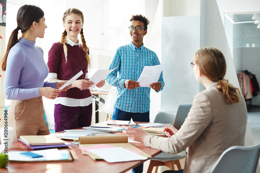 Three successful students making reports at seminar while standing in front of their teacher