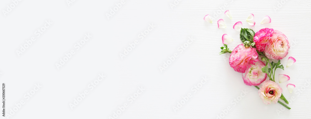 Image of delicate pastel pink beautiful flowers arrangement over white wooden background. Flat lay, top view.