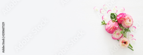 Image of delicate pastel pink beautiful flowers arrangement over white wooden background. Flat lay, top view. © tomertu
