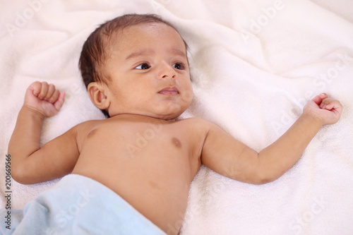 Playful newborn baby lying down in bed