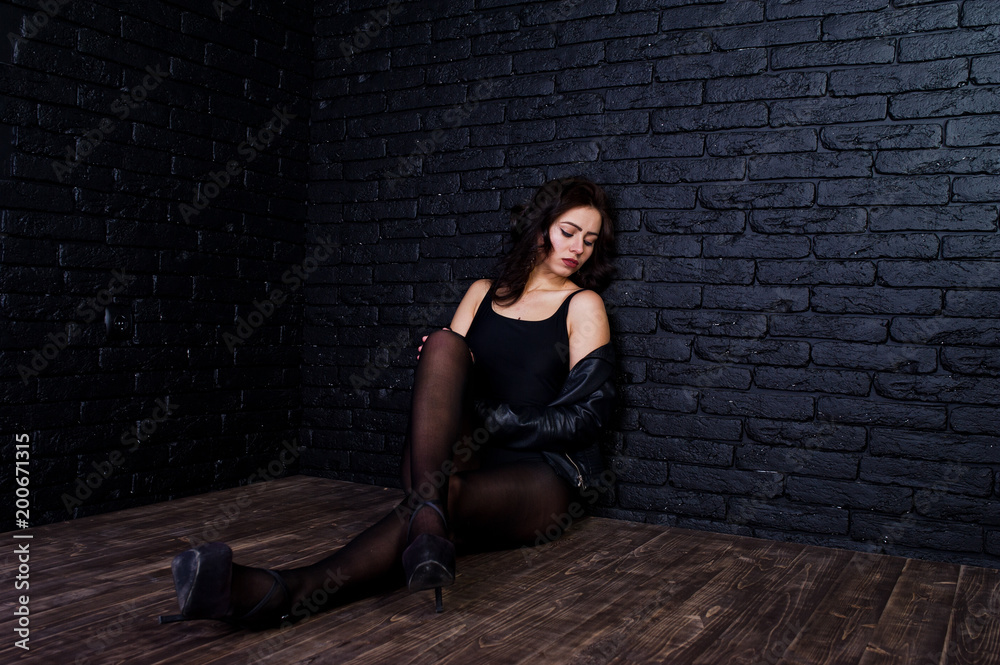 Studio portrait of sexy brunette girl in black leather jacket against brick wall. Studio portrait of sexy brunette girl in black leather jacket against brick wall.