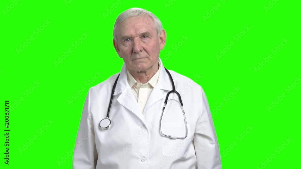 Serious grave earnest doctor. Portrait of frowning old doctor touching his face, green hromakey background for keying. Serious grave earnest doctor. Portrait of frowning old doctor touching his face, green hromakey background for keying.