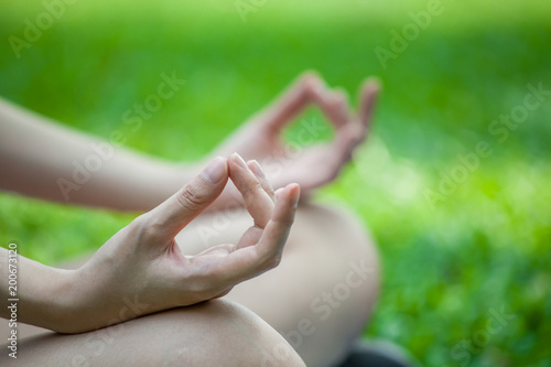 Close up hands woman meditation in the lotus position, hand of young fitness girl doing yoga in park