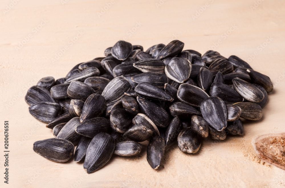 Sunflower seeds against the background of a light coloured wood texture.. Sunflower seeds against the background of a light coloured wood texture..