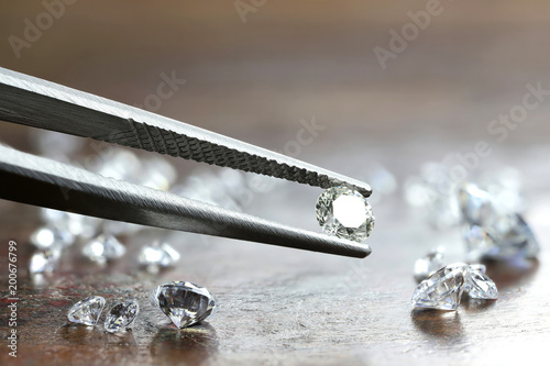 brilliant cut diamond held by tweezers photo