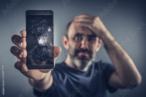 Photos Mann hällt kaputtes Handy in der Hand