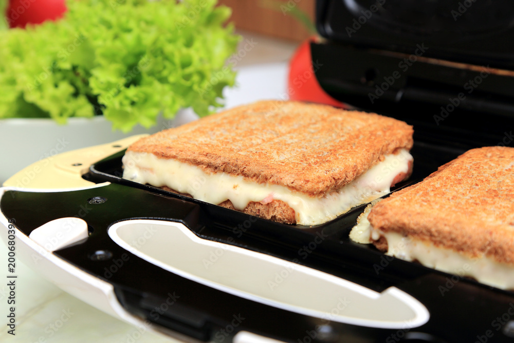 Fototapeta premium Posiłek z tostów robionych w tosterze, sałaty, papryki, kiełbasy szynkowej i herbaty owocowej.