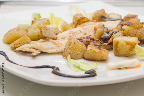 sea bass in the dish with potatoes and salad