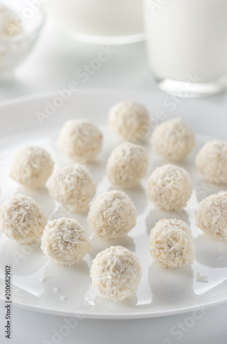 Coconut candies on a background of a jug and a cup of milk and bowls of cottage cheese