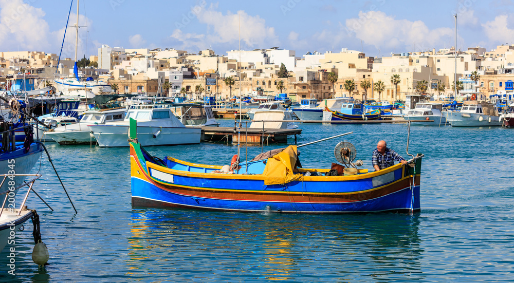 Marsaxlokk, Malta. Fisherman in a traditional colorful boat at the port of Marsaxlokk