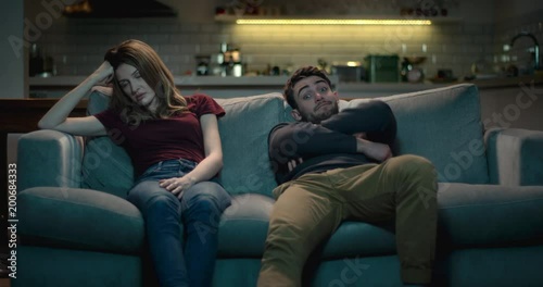 Frustrating relationship - couple at home sitting on a sofa struggling with each others company.