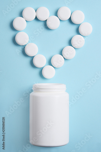 Symbol of the heart with pills  pouring out from a white plastic jar.