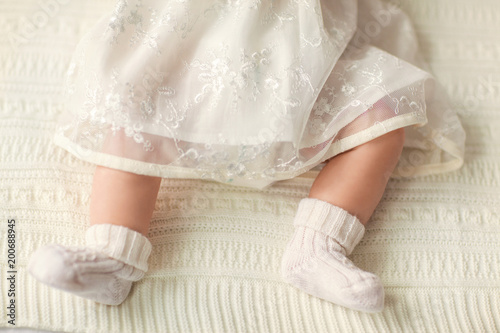 legs of a little girl with a white bow lies on the couch, on a white background.