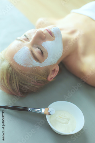 Face mask.Beautiful young girl at spa ,cosmetician woman applying facial mask.