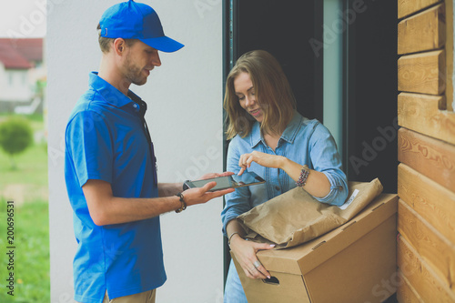 Smiling delivery man in blue uniform delivering parcel box to recipient - courier service concept. Smiling delivery man in blue uniform photo