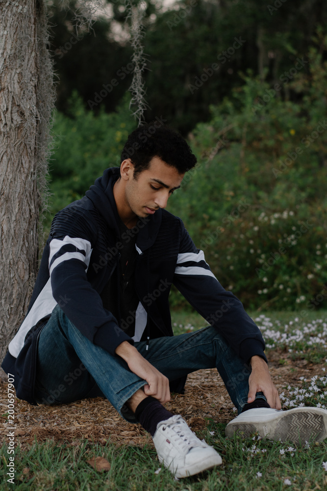 Handsome Young Male Model Sitting by a Tree in the Woods Handsome Young Male Model Sitting by a Tree in the Woods