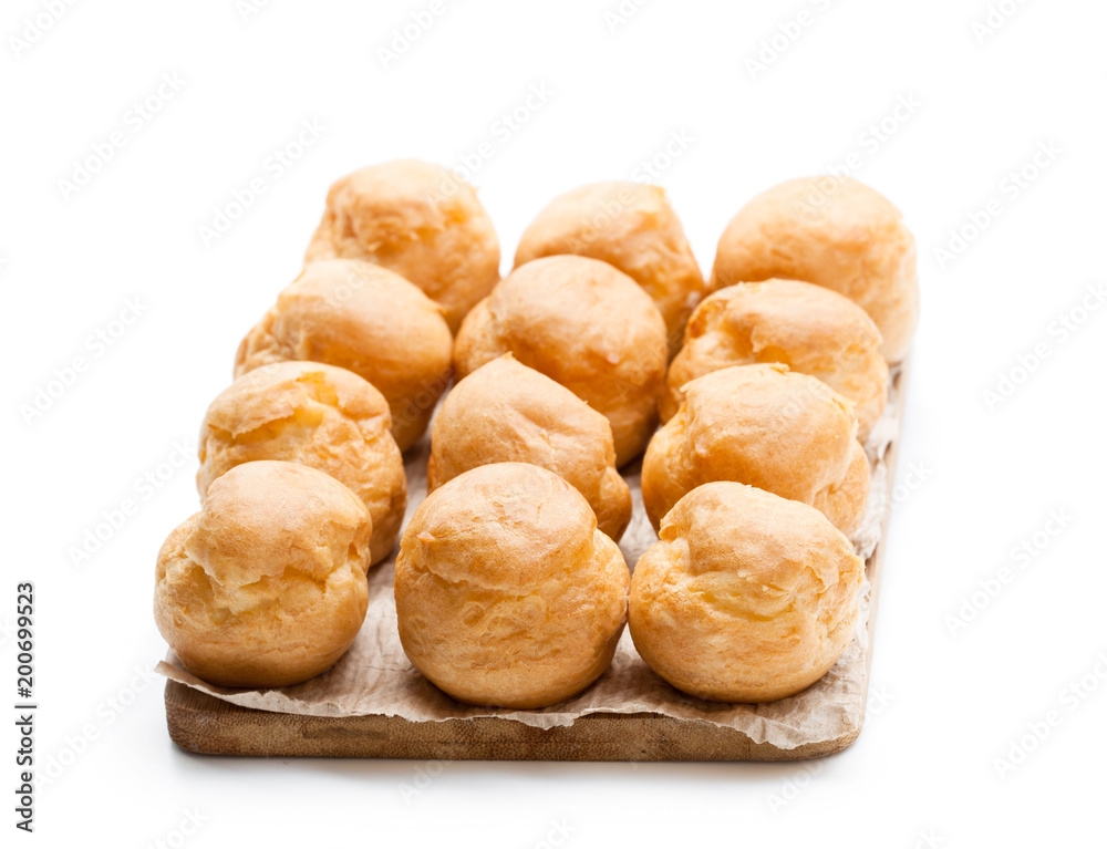 Homemade profiteroles on wooden board isolated on white Homemade profiteroles on wooden board isolated on white